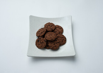 A plate of chocolate chip cookies sitting on a white surface