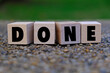 © Ardini - a wooden cube with the word DONE with background of blurry green