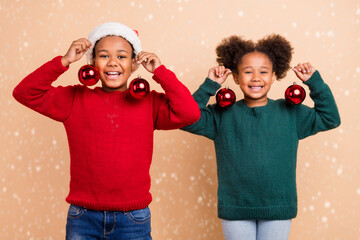 Wall Mural - Photo of two funny cute kids brother sister hold tree baubles wear x-mas hat jumper isolated beige color background