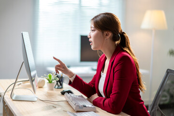 Wall Mural - A woman in a red jacket is pointing at something on a computer monitor