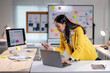 © Wasana - A woman in a yellow jacket is using a laptop computer
