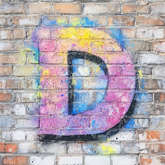 Colorful graffiti letter D on a brick wall