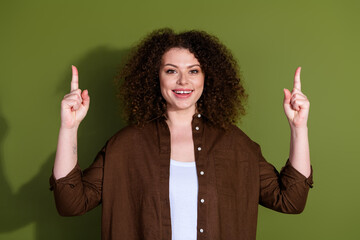 Wall Mural - Photo of pretty young woman point fingers up empty space wear brown shirt isolated on khaki color background