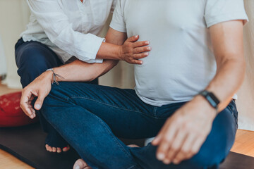 A man and a woman practicing mindful breathing together during a meditation session, seated on mats