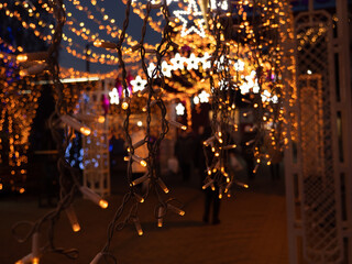 Christmas and New Year holidays decorations of streets with trees and shops with multicolored christmas string fairy lights glowing in the darkness outdoors. Winter holidays celebration concept.