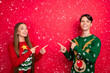 © deagreez - Photo of promoter couple indicate finger empty space novelty wear ugly sweater isolated red color background