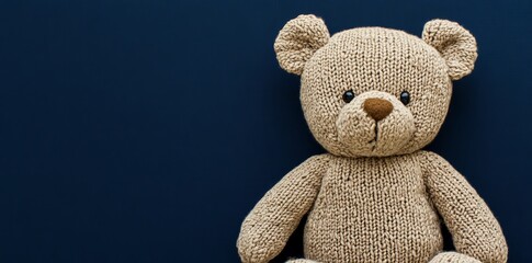 This knitted teddy bear with an orange sweater stands out on a dark background