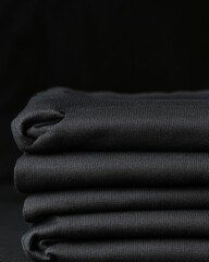 Wall Mural - A stack of neatly folded black t-shirts is displayed against a dark background