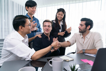 Diverse group of office employee worker shake hand after making agreement on strategic business marketing meeting. Teamwork and positive attitude create productive and supportive workplace. Prudent