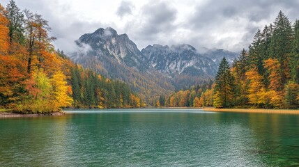 Wall Mural - A scenic view of a lake surrounded by trees with fall foliage and mountains in the background.