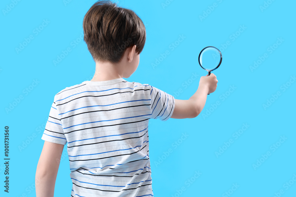Little boy with magnifier on blue background