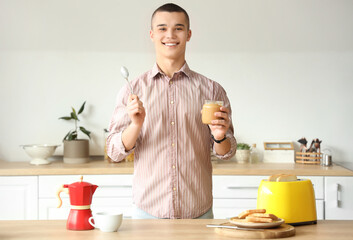 Wall Mural - Happy young man with tasty nut butter in kitchen