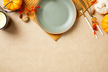 Elegant autumn table setting with a plate, golden cutlery, and festive fall decorations like pumpkins and leaves. Thanksgiving dinner concept