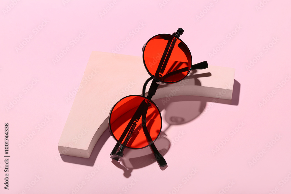 Decorative podium with stylish sunglasses on pink background