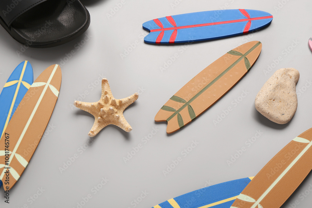 Different mini surfboards, starfish and stone on grey background