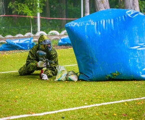 Wall Mural - paintball sport player in protective uniform and mask playing with gun outdoors