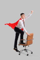 Wall Mural - Businessman with superhero cape and office chair on light background