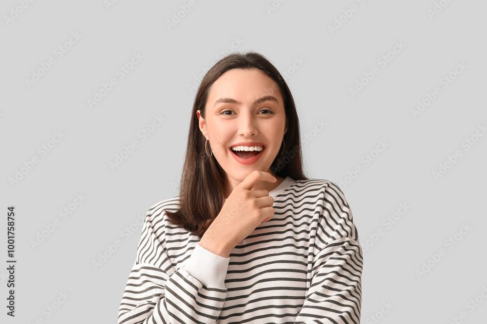 Smiling young woman on grey background