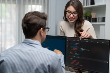 Woman colleague standing opposite to man programmer working on desk to discuss coding website software system project on two pc screen, comparing with typing full stack data prompt design. Postulate.