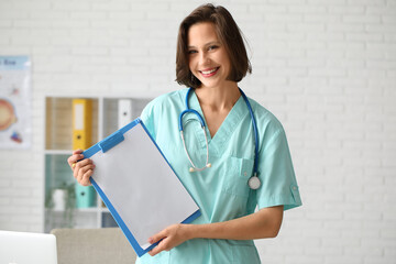 Canvas Print - Beautiful female doctor with clipboard in clinic