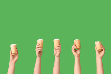 Wall Mural - Female hands with sweet ice-cream in waffle cups on green background