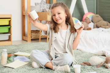 Sticker - Happy little girl with yogurt packs sitting on floor in room