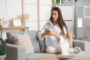 Sticker - Young woman using mobile phone on grey sofa in light living room