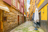 Fototapeta Uliczki - The narrow, colorful hillside alleys and streets full of shops, cafes and restaurants in the historic Ribeira district of Porto Portugal.