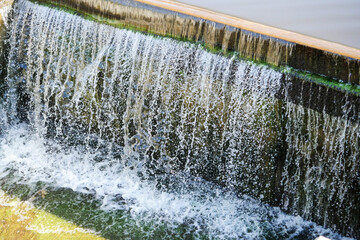 Wall Mural - water falling from a dam with many droplets. power and energy of water. dark concrete wall backgroun