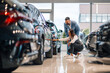 © Zamrznuti tonovi - Woman and man examining cars on the showroom floor, discussing details