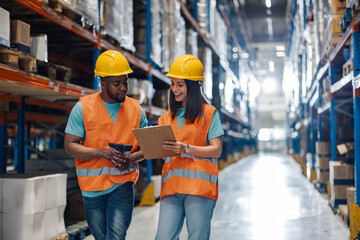 Wall Mural - Two diverse warehouse workers sharing a discussion in equipment