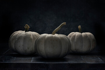 Three  white pumpkins lit in dramatic back light