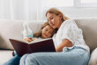 © SHOTPRIME STUDIO - Mother and daughter bonding time enjoying a story together on the couch in a cozy living room