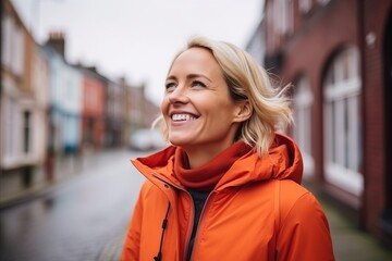 Wall Mural - Portrait of a happy woman in an orange jacket smiling at the camera