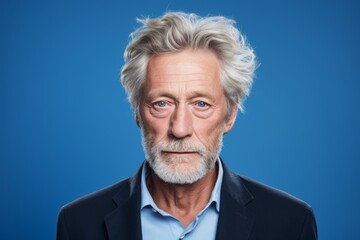 Wall Mural - Portrait of a senior man with grey hair and beard on blue background