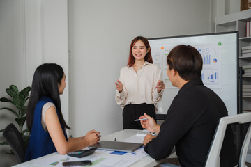 Confident Presentation: A professional woman confidently delivers a presentation to two colleagues in a modern office setting, showcasing her expertise and engaging her audience.  