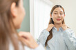 © Pormezz - Get dress, pretty asian young woman, businesswoman standing wearing striped shirt, female getting dressed preparing before go to work looking reflection in the mirror in the morning at home.