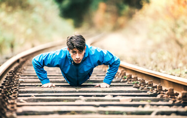 Sporty man exercising on old unused rails in the middle of nature. Morning workout for young man.