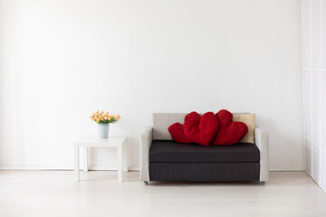 Gray sofa with gifts for a holiday in the interior of a white room with a window