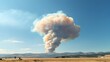 © thanarak - Dramatic and expansive wildfire smoke plume rising high into the sky visible from miles away across the landscape  The towering cloud of smoke billows and spreads out