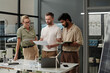 © TrueFrame Collective - Group of young intercultural architects preparing for presentation of new project while standing by workplace