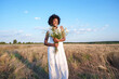 © Westend61 - Happy young woman holding bunch of daises in field under sky