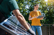 © Westend61 - Woman using tablet PC by engineer holding solar panel