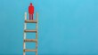 © Vilaysack - A small red figure stands at the top of a wooden ladder, symbolizing success, achievement, and career growth, set against a blue background.