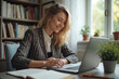 © Creative Clicks - A woman is sitting at a desk with a laptop and a book