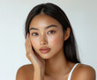 © Itsaya - stunning Asian model gently touches her cheek, showcasing her smooth skin and natural beauty. This image captures essence of elegance and grace, perfect for cosmetics advertisement