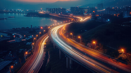 Poster - Aerial view of a busy highway at night, headlights and taillights of cars create a flowing stream of light. The road is illuminated by street lights and the surrounding area is dark.