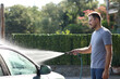 © Antonioguillem - Man cleaning car with water using hosepipe