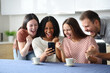 © Antonioguillem - Excited friends celebrating success checking phone at home