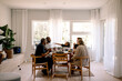 © Maskot - Happy multigenerational family having lunch while sitting together at dining table in home